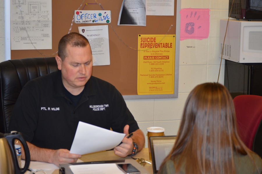 Officer Russ Wilde, a member of the Hillsborough Police Department, helps a student in his office.