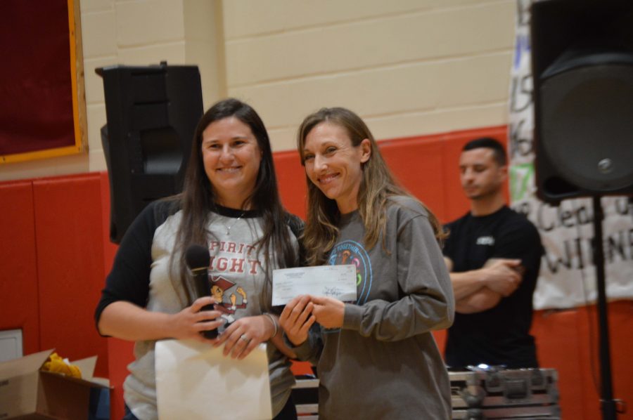 Student Council Adviser Caryn Morrison presents a check for $4,000 to Steps Together board member Melissa Almendinger .