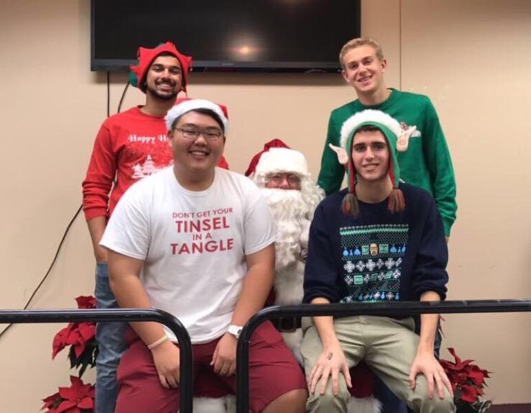 Senior class cabinet members, clockwise from upper left, Jay Raje, Carter Altman, Eric Ross, and Jordan Kang pose with Santa Claus at   the Safe + Sound Holiday Party.