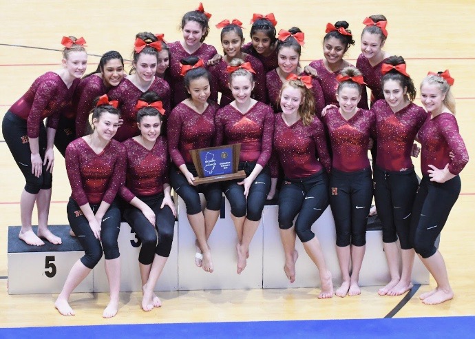 The surging gymnastics team gathers around the podium to celebrate its Sectional title.