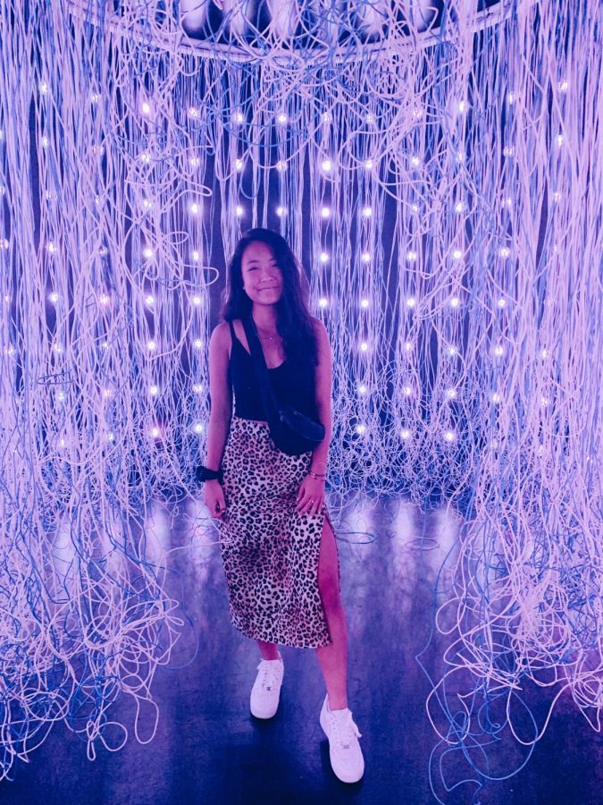 Writer Emily Chu poses in front of an exhibit at Wndr Museum.