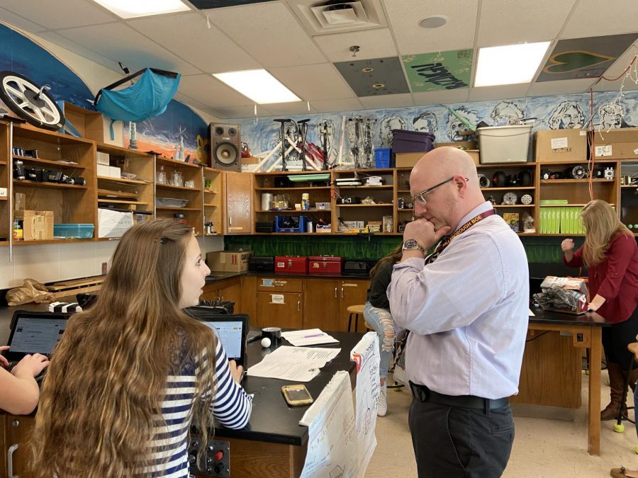 Physics teacher Christopher Aleo thoughtfully helping students with their Egg Slam projects.