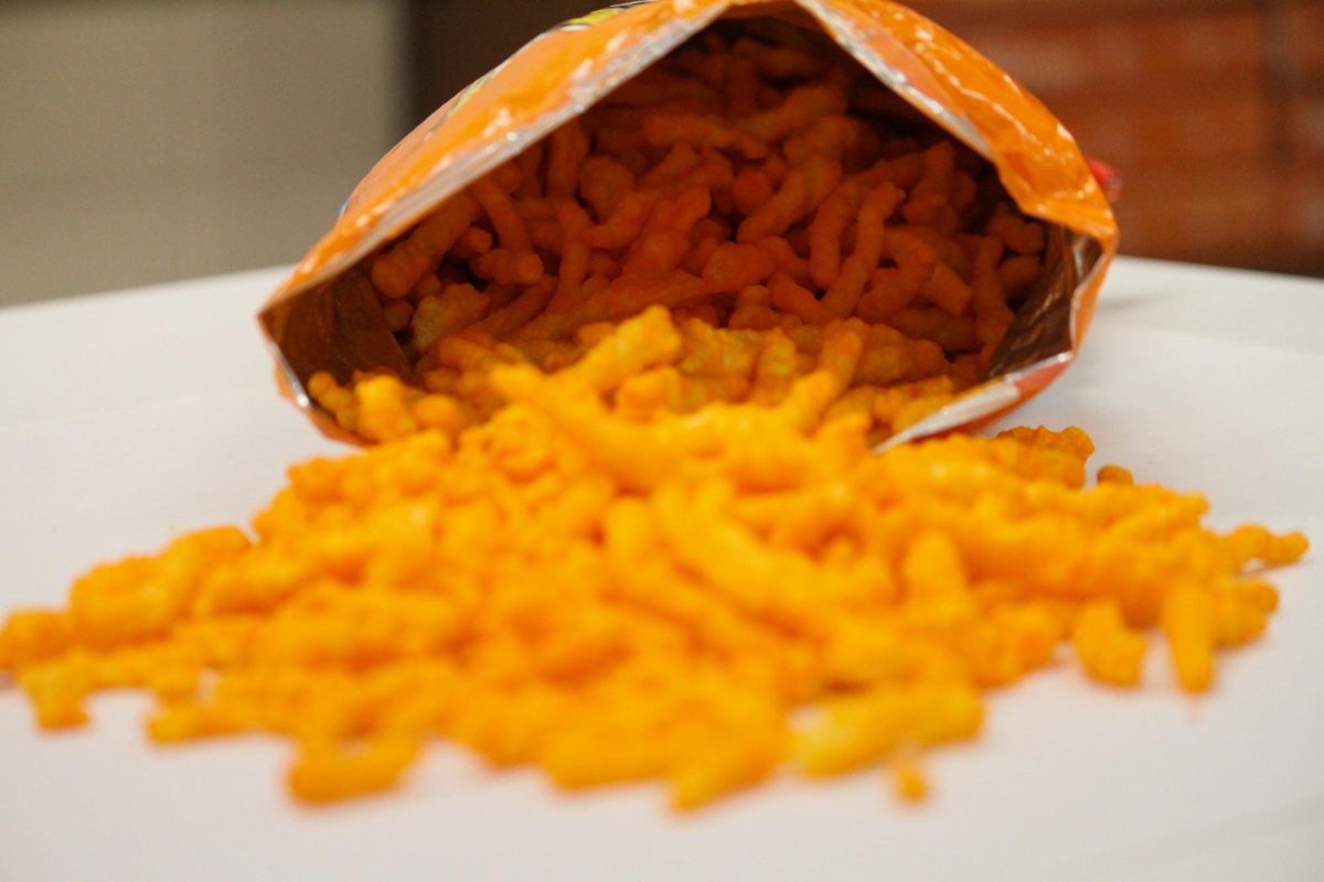 A bag of Cheetos, a salty cheese-flavored snack famous for leaving orange stains on the hands of consumers, spills onto a table.