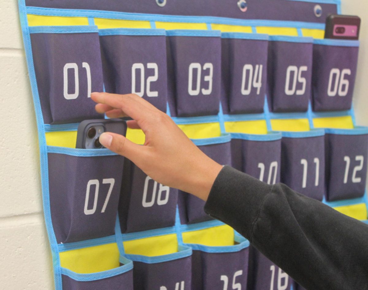 Students in period 10 AP Computer Science Principles place their phones in holders before class