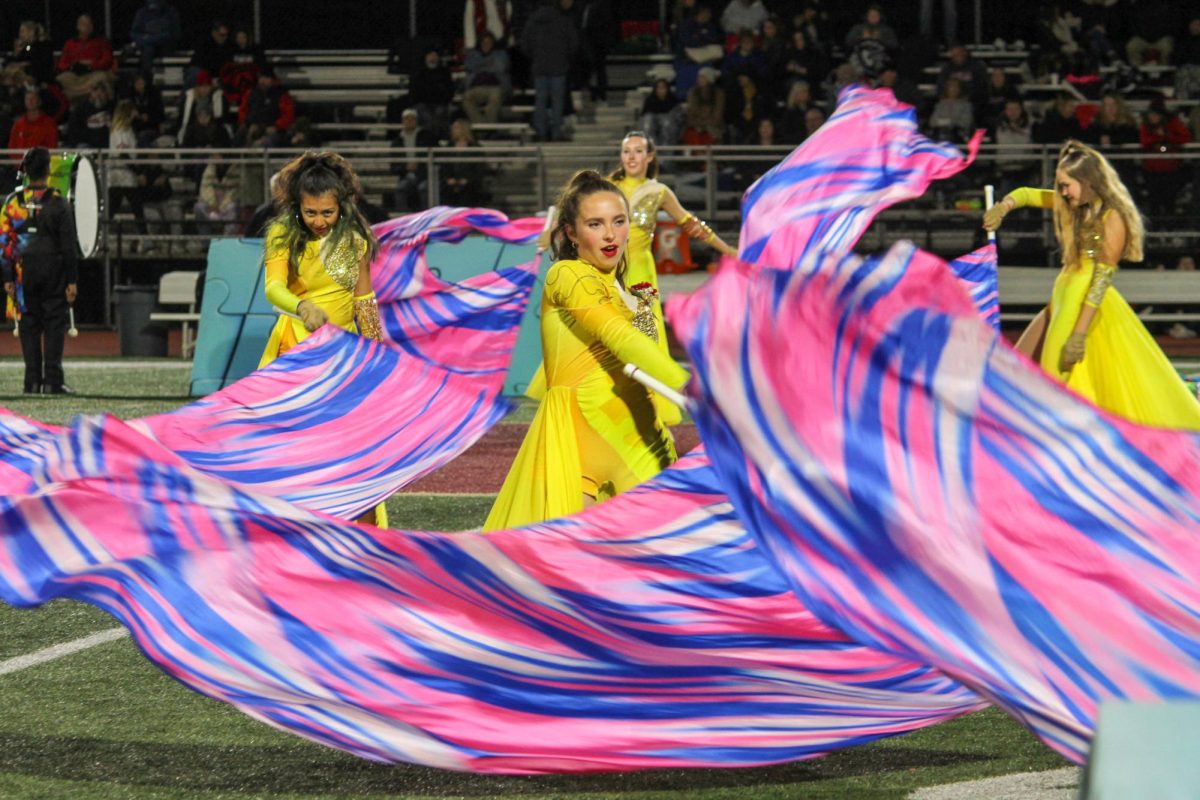 Senior Ana Mellone twirls her flag in unison with her fellow Color Guard members 