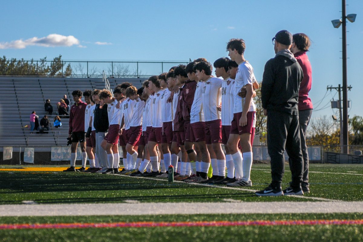 Standing at midfield, the boys varsity soccer team lines up with the team's coaches before the October 16 game. 