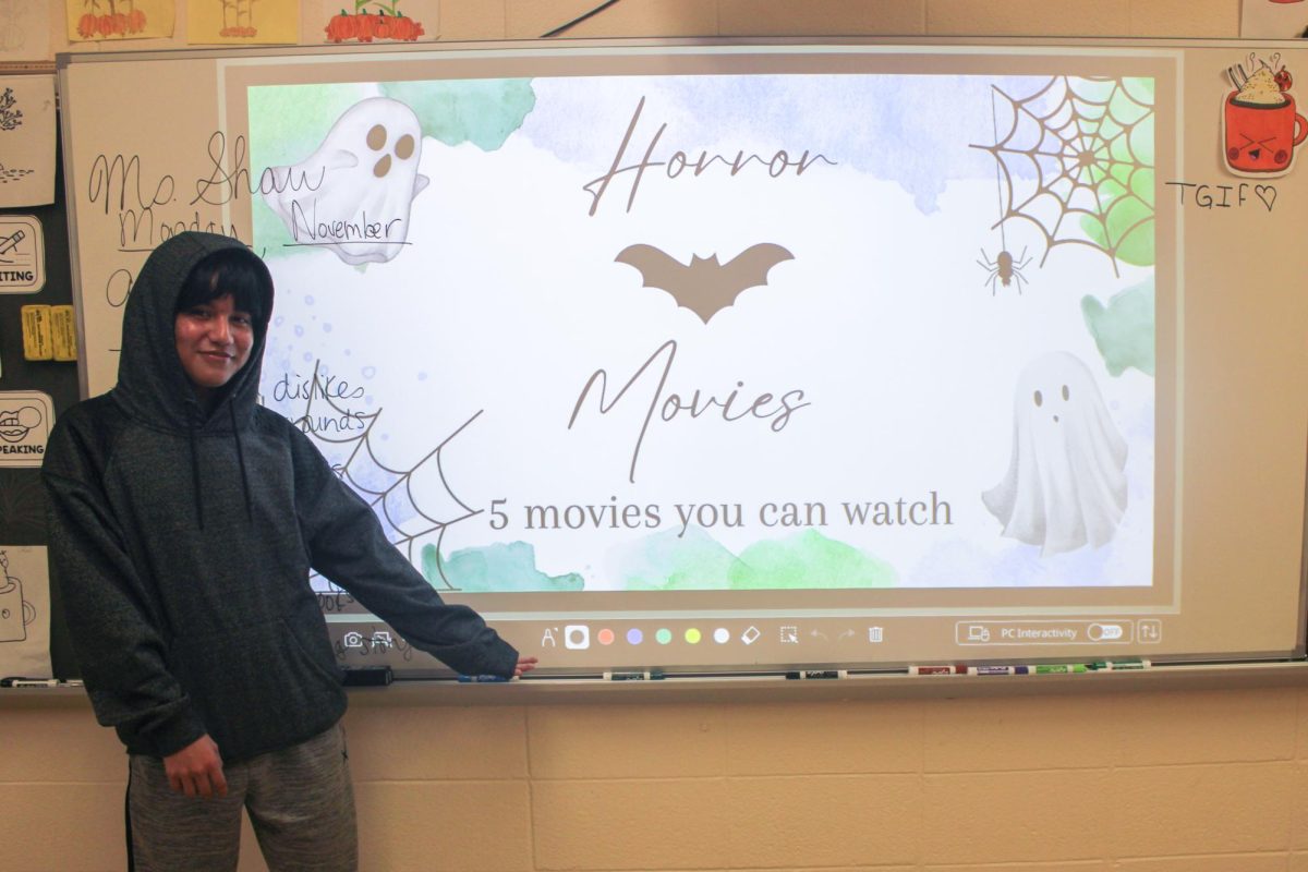 Kelvin stands in front of the class with his horror movie slideshow