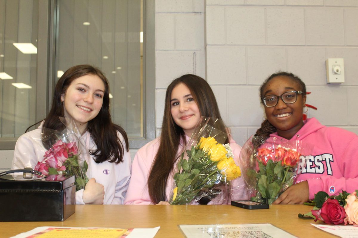 HHS Cheer members (left to right: Heather Mullins, Emily Corsello, and Nayana Downing) sell roses as part of their fundraiser.