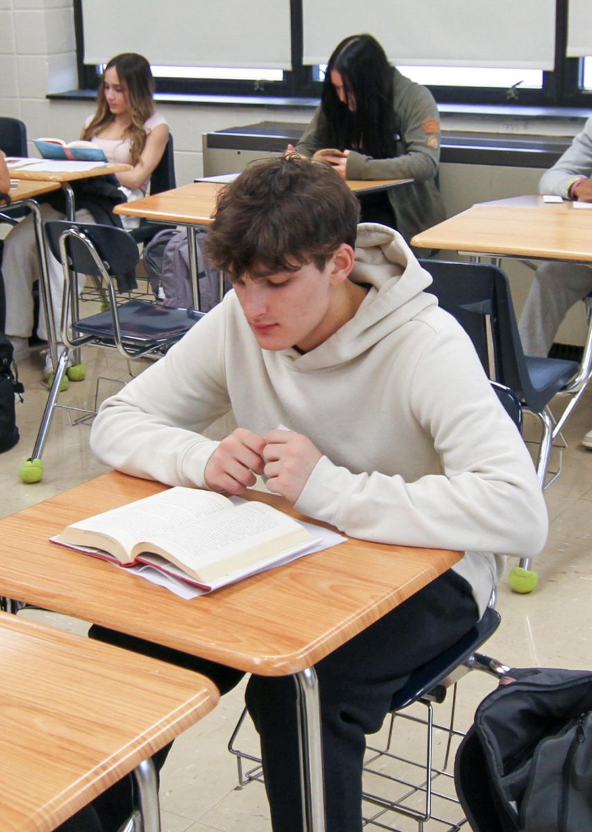 Owen Miller reads silently at the start of English II CP with Mr. Thomas Kida. 