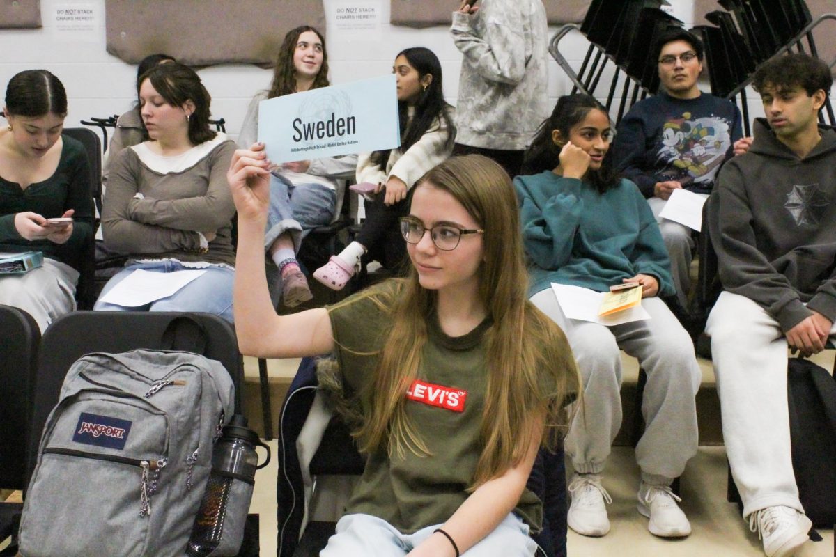 Calissa Churchill raises her placard, representing Sweden during a debate meeting.