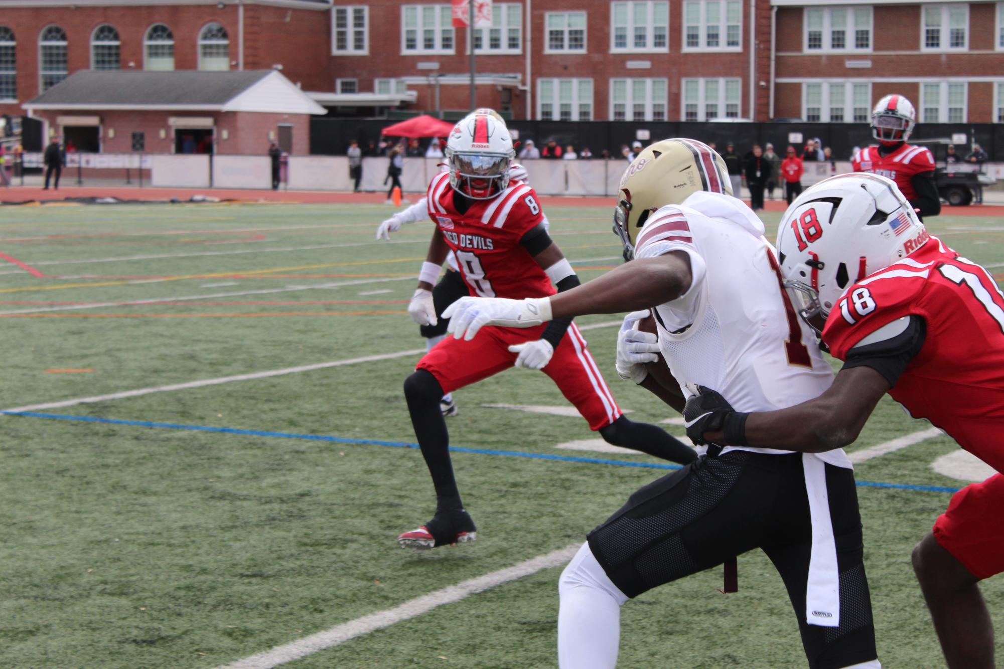 Senior Hameed Kamara runs the ball down towards the end zone, while defenders surround him looking for a tackle.