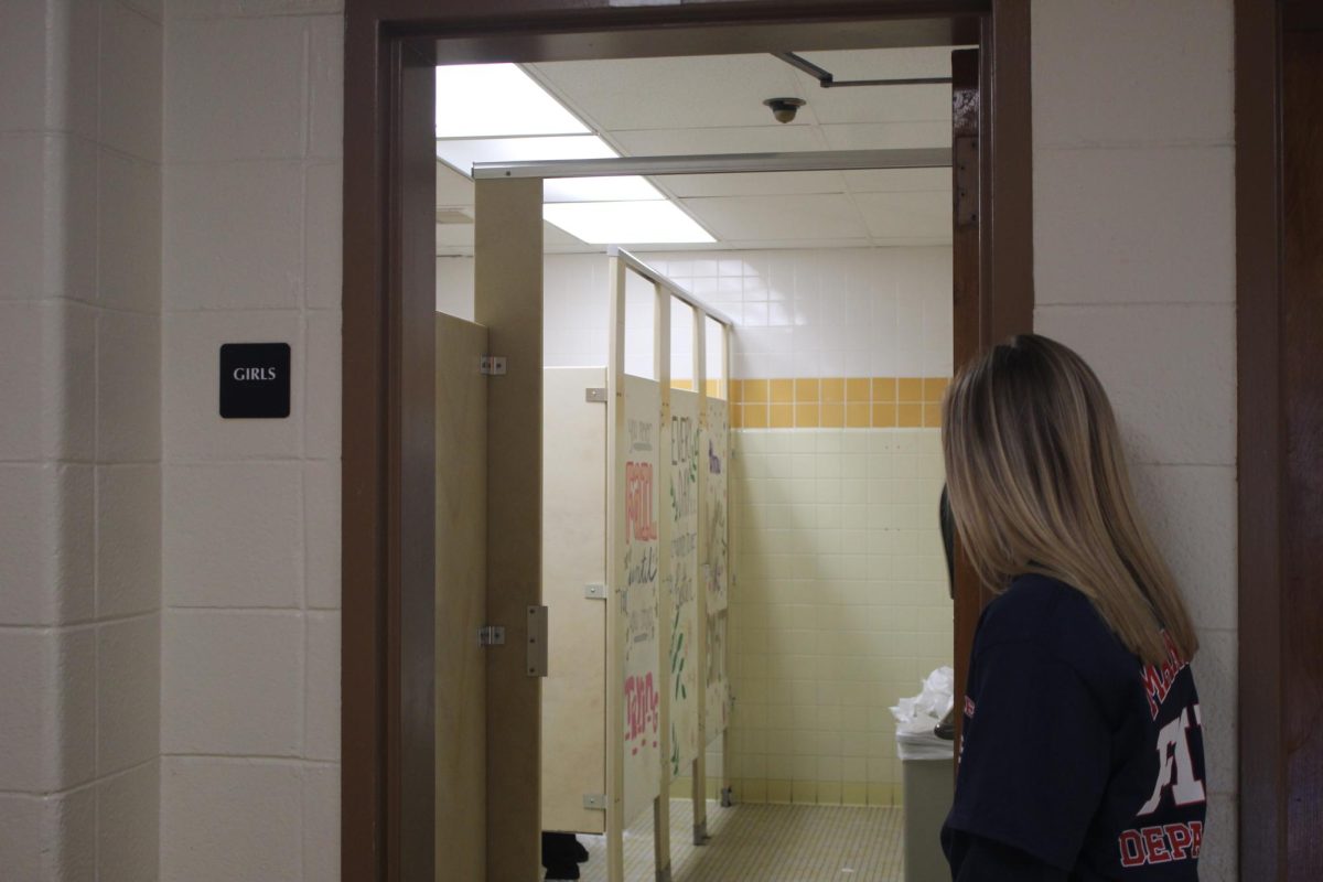 A student waits to enter the girls’ bathroom in the 200s.