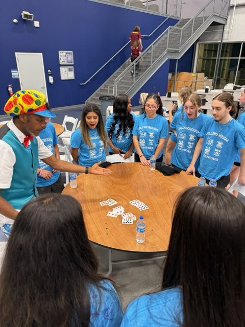 A magician performs a trick for a group of interested students.