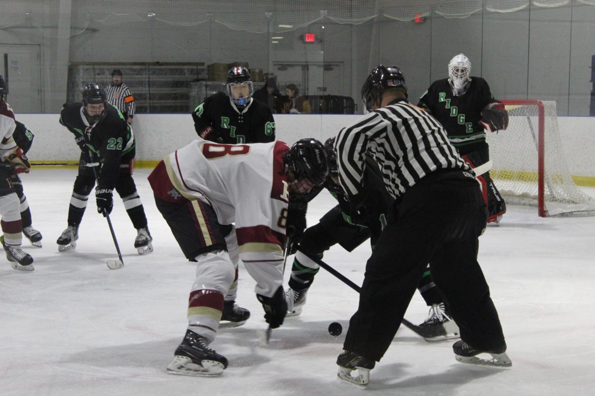 Senior Colin Marley fights for the puck in an intense face off with a Basking Ridge player, looking for an open teammate.