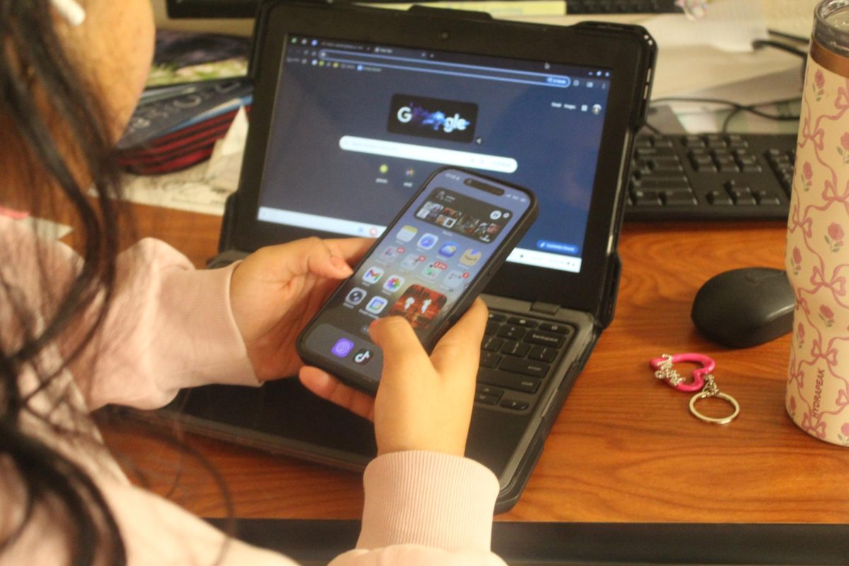 A student sits distracted by their phone in class. 